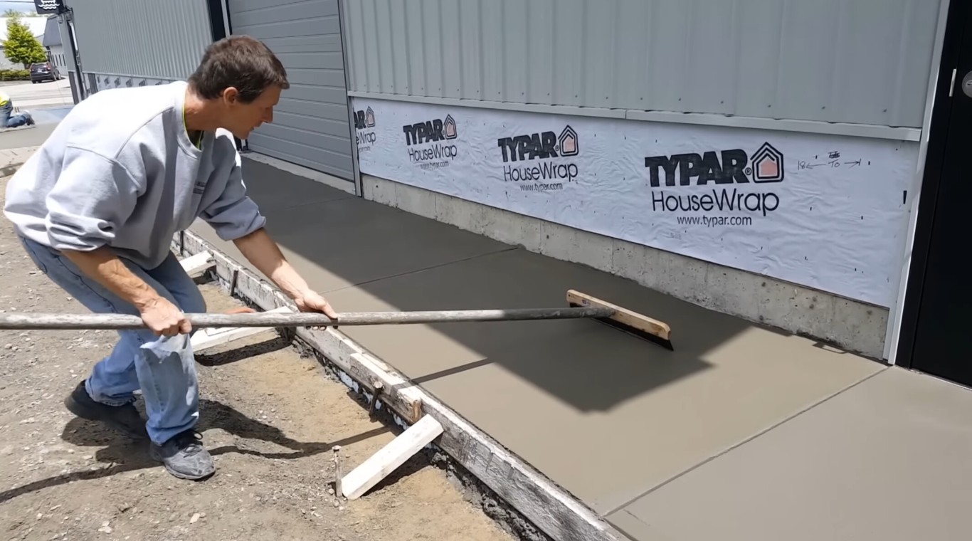 Professional concrete contractor pouring and leveling fresh concrete